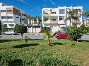 a park with palm trees and a building at Agreable appartement dans une résidence calme sécurisée in El Harhoura