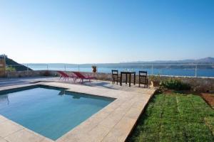 a swimming pool with a table and chairs and the water at Aptera Dream Apartment in Áptera