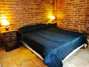 um quarto com uma cama e uma parede de tijolos em Complejo Hatun Yaya em Mendoza