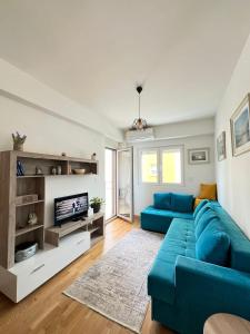 een woonkamer met een blauwe bank en een tv bij Odmor u Podgorici. in Podgorica