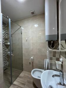 een badkamer met een douche, een wastafel en een toilet bij Odmor u Podgorici. in Podgorica