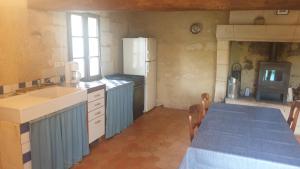 eine Küche mit einem Tisch und einem weißen Kühlschrank in der Unterkunft La maison de falun in Ambillou-Château