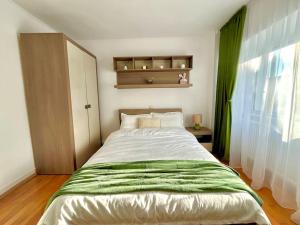 a bedroom with a bed with a green blanket on it at Valcea Northside Spacious Apartment in Râmnicu Vâlcea
