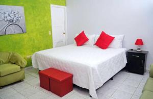 a bedroom with a large white bed with red pillows at Hotel Boutique Rosse in San Pedro Sula