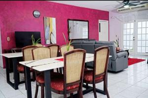 Hotel Boutique Rosse في سان بيدرو سولا: غرفة طعام مع طاولة وكراسي وجدار وردي