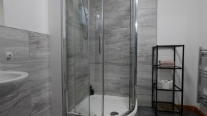 La salle de bains est pourvue d'une douche avec une porte en verre. dans l'établissement The StayLuxe Apartment Manchester, à Manchester