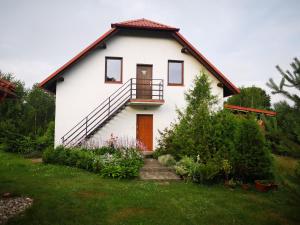 een wit huis met een veranda en een balkon bij Borowy Zakątek in Stara Kiszewa