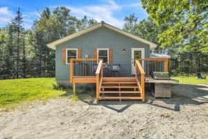a tiny house with a porch and a table and a laptop at Cozy cottage in the woods in Surry