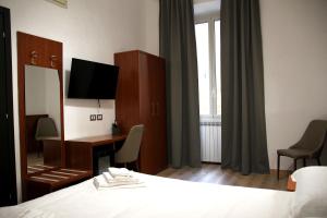 um quarto de hotel com uma cama, uma secretária e um espelho em Principe Guesthouse powered by Joyful Guesthouse em Roma