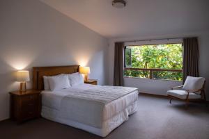 a bedroom with a bed and a window and a chair at Bow Street Studios - The Apartments in Raglan