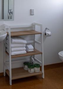 a bathroom with a shelf with towels and a sink at Bow Street Studios - The Apartments in Raglan