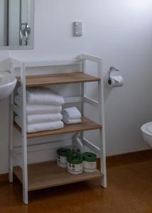 a bathroom with a shelf with towels and a sink at Bow Street Apartments & Cottage in Raglan