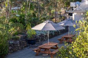 two picnic tables with umbrellas on a patio at Bow Street Apartments & Cottage in Raglan