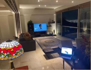 ein Wohnzimmer mit einem Laptop und einem TV in der Unterkunft Departamento de Lujo en Chipinque. La mejor vista. in Monterrey