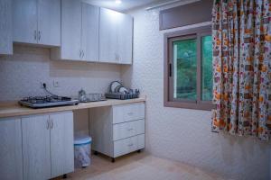 eine Küche mit weißen Schränken und einem Fenster in der Unterkunft hotel el amri akchour in Akchour