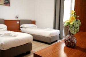 um quarto com duas camas e um vaso com flores sobre uma mesa em Principe Guesthouse powered by Joyful Guesthouse em Roma