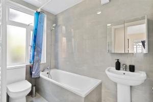 a white bathroom with a sink and a toilet at Beautiful Wembley Gem - Parking -Sleeps 14 in London