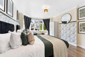 a bedroom with a large white bed with pillows at Beautiful Wembley Gem - Parking -Sleeps 14 in London