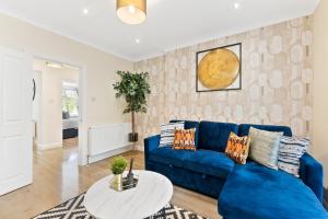 a living room with a blue couch and a table at Beautiful Wembley Gem - Parking -Sleeps 14 in London