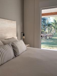 a bedroom with a white bed with a large window at Casa Country Altos Arrayanes in Mercedes