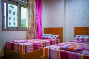 Akchourにあるhotel el amri akchourのピンクのカーテンが備わるドミトリールームのベッド2台