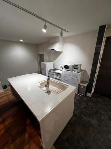una cocina con una isla blanca en una habitación en 貸し切りゲストハウスsai2nd en Yasugi