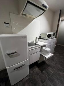 eine kleine Küche mit einer Spüle und einer Mikrowelle in der Unterkunft 貸し切りゲストハウスsai2nd in Yasugi