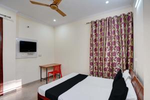 a hotel room with a bed and a tv at Super OYO OM SAI RAM GUEST HOUSE in Gurgaon