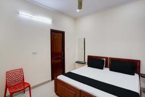 a bedroom with a bed and a red chair at Super OYO OM SAI RAM GUEST HOUSE in Gurgaon