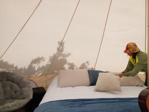 モンテベルデ・コスタリカにあるBetter Life Mountain Camp Monte Verdeのテントのベッドに腰掛けている女性