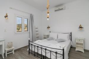 a white bedroom with a bed and a window at Loulou House in Agia Kiriaki Beach