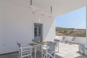 a white dining room with a table and chairs at Loulou House in Agia Kiriaki Beach +34 photos