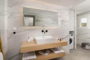 a white bathroom with a sink and a washing machine at Loulou House in Agia Kiriaki Beach