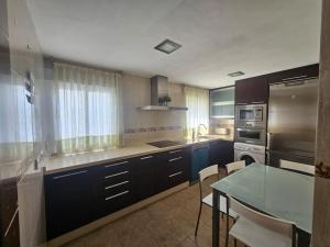 Una cocina con gabinetes azules y una mesa con una mesa de vidrio. en Azahar, en Córdoba