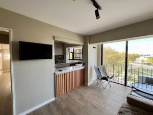 uma sala de estar com uma televisão na parede e uma cozinha em la vista em Colónia do Sacramento