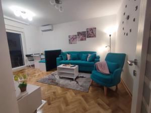 a living room with a blue couch and two chairs at Apartman PINA Vrnjacka Banja in Vrnjačka Banja