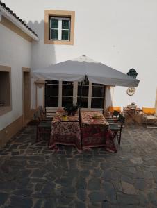 una mesa con sombrilla en el patio en Casa Do Ginjal by NaturAlegre en Marvão