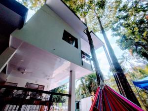 une maison blanche avec un hamac devant elle dans l'établissement Casajungla Hostel, à Jacó