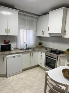 uma cozinha com armários brancos, uma mesa e um lavatório em Casa del Carmen em Lorca