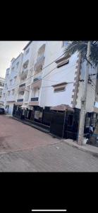 a large white building with a palm tree in front of it at Joli appartement ngor / Almadies in Ngor