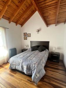 una camera con un grande letto e un soffitto in legno di Departamentos Turismo de un dormitorio y dos dormitorios a San Martín de los Andes
