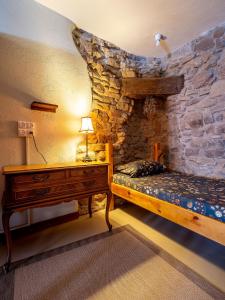 sypialnia z łóżkiem, biurkiem i kamienną ścianą w obiekcie Albergue de peregrinos en CIRAUQUI - CASA MARALOTX Camino de Santiago w mieście Cirauqui