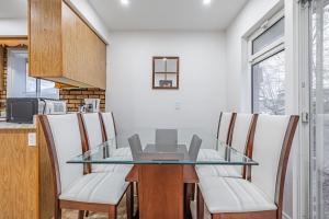 a dining room with a glass table and chairs at Littlewood Properties in Toronto