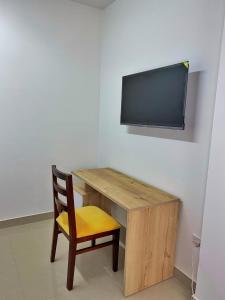escritorio de madera con silla y TV de pantalla plana en HOSPEDAJE BOGOTA CENTRO, en Bogotá
