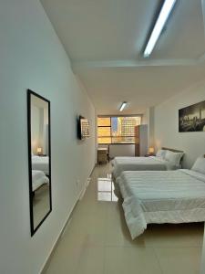a white bedroom with two beds and a mirror at HOSPEDAJE BOGOTA CENTRO in Bogotá