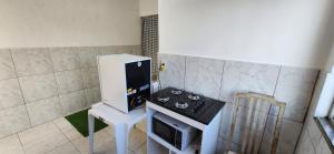 a small kitchen with a stove and a microwave at Kitinet aconchegante em Nova Iguaçu in Nova Iguaçu