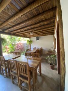 uma sala de jantar com uma mesa de madeira e cadeiras em Pousada Dendê Caraiva em Caraíva