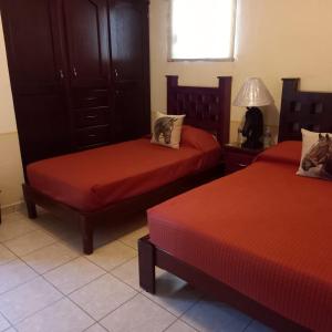 a hotel room with two beds with red sheets at Roselyn in Bernal