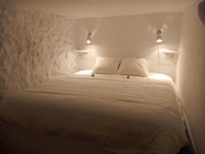 Un dormitorio con una cama blanca con dos luces. en Casamar en Almería