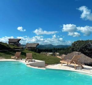 a swimming pool with two chairs and a view of the mountains at Margarita Ecovillage in Miches